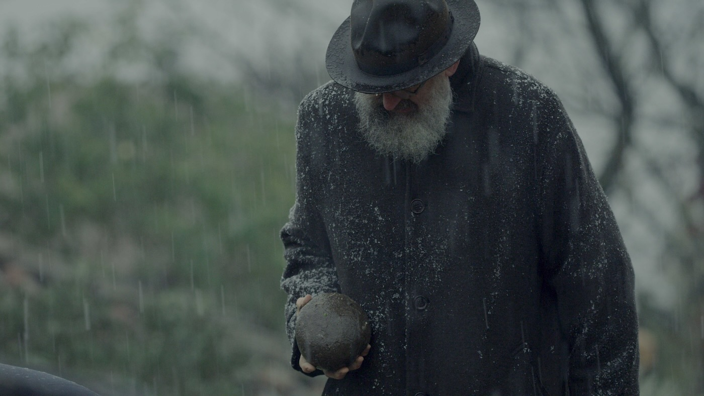 Scene from the documentary Architecton (2025) showing Italian architect Michele De Lucchi holding a stone in his hand.